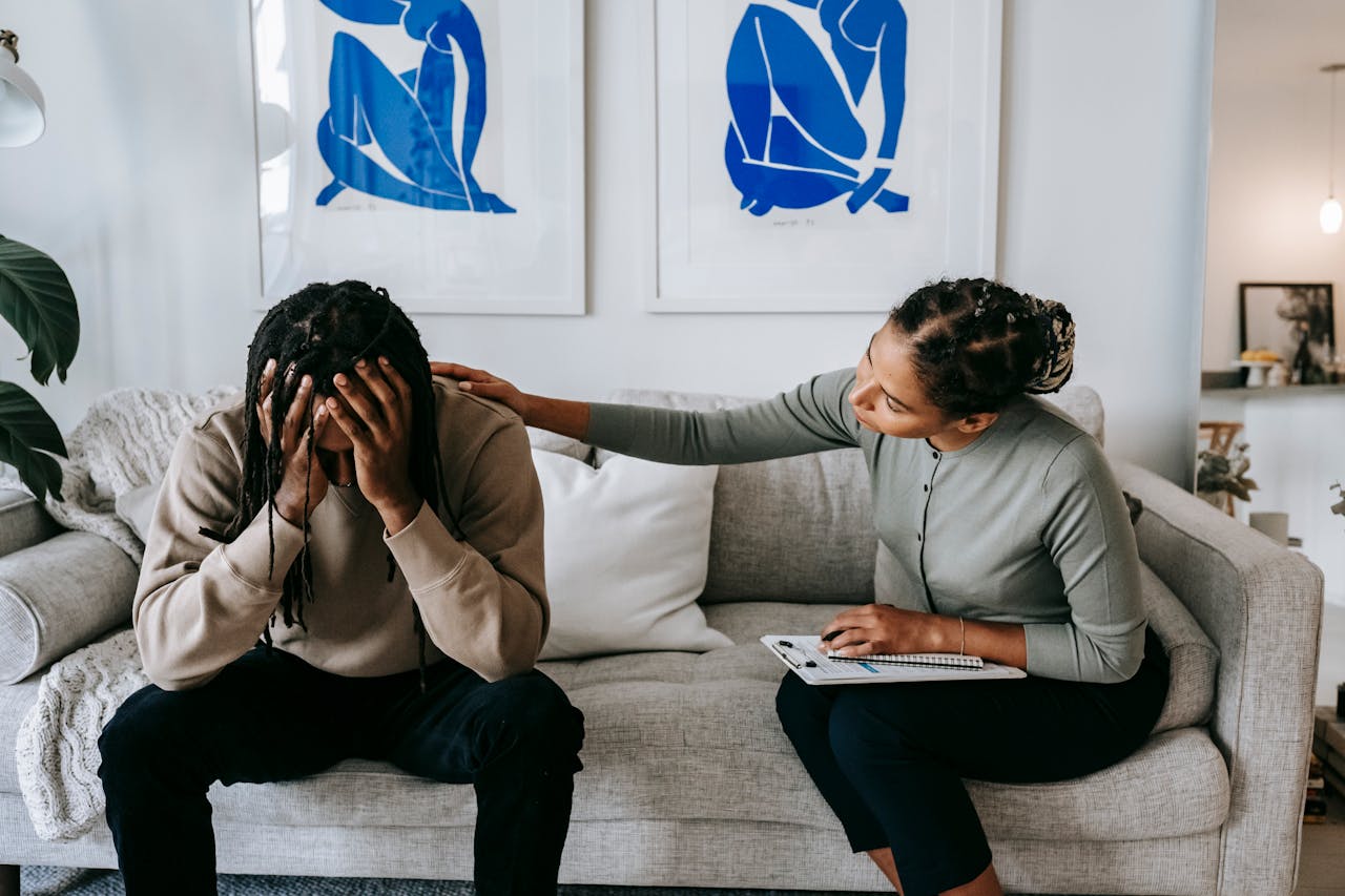 A couple sharing a moment of support and understanding on a living room sofa, depicting comfort.